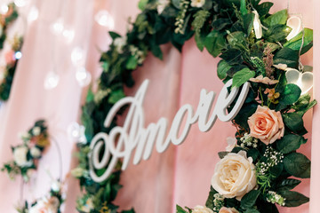 Amore wooden inscription in a frame of greenery and flowers in blur bokeh