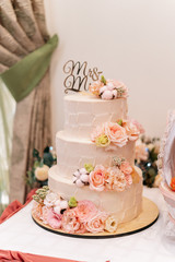 Three-tier wedding cake nested with flowers and roses