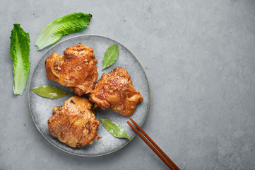 Filipino Chicken Adobo on gray plate on concrete backdrop. Chicken Adobo is Filipino cuisine dish of braised chicken thighs, soy sauce, vinegar, black pepper and bay leaves. Filipino food. Copy space