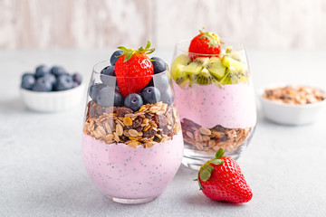 Chia seeds pudding with granola, blueberry and strawberry in glasses. Yogurt with chia seeds, berries, kiwi and muesli for healthy breakfast, copy space