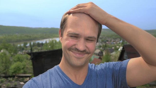 portrait, balding young man in the countryside looking at the camera, smiling