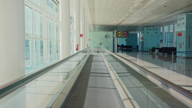 View of bright and open, well lit empty terminal of airport. Global tourism and travel collapse crisis, empty airports and disrupted travel connections. Moving walkway to gate for delayed flight