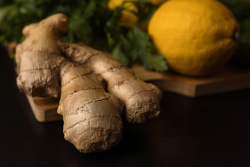Components of Asian cuisine, healthy food. Ginger close-up and on a background of lemon on a wooden board and a dark background in the lower key.