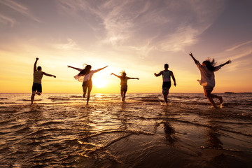 Five happy friends runs at sunset beach - obrazy, fototapety, plakaty