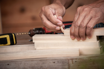 Hands of a carpenter taking measurement of a wooden plank