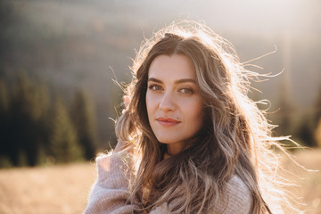 Portrait of a young beautiful girl with long hair in autumn mountains at sunset.