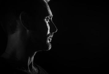 Dramatic profile portrait of male person on dark background