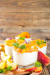 Curd or yogurt dessert with canned and fresh peaches, on wooden rustc background. Summer breakfast fruit dessert.