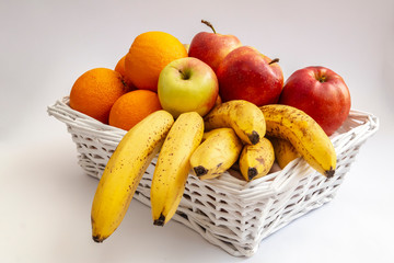 organic fruits, apples, oranges and bananas in a white basket
