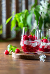 Homemade cottage cheese with fresh raspberries in a glass glass on a rustic wooden background. Dietary breakfast. Russian cottage cheese with berry and mint.