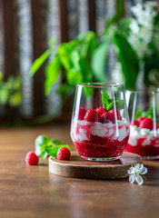 Homemade cottage cheese with fresh raspberries in a glass glass on a rustic wooden background. Dietary breakfast. Russian cottage cheese with berry and mint.