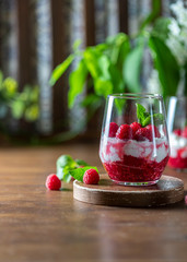 Homemade cottage cheese with fresh raspberries in a glass glass on a rustic wooden background. Dietary breakfast. Russian cottage cheese with berry and mint.
