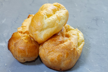 three eclairs from custard dough on a gray background