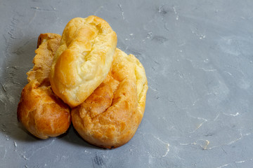 three eclairs from custard dough on a gray background