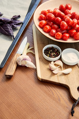 High angle view of oven tray, plate and cutting board with ingredients near knife on wooden background