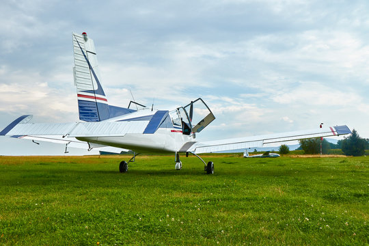 Back view of Zlin Z-43 four-seat airplane standing on a grass runway.  Low-wing monoplane.