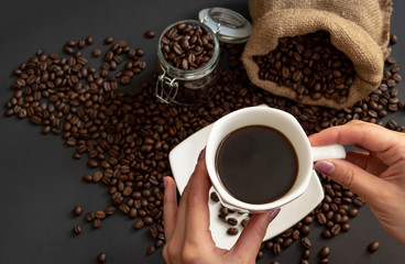 Morning black coffee in a Cup. The woman holds the Cup and inhales the coffee aroma