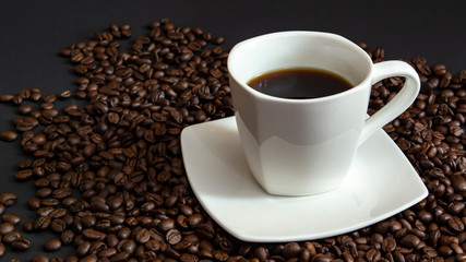 a hot Cup of espresso. It looks perfect in a white Cup on a saucer with coffee beans on a black background