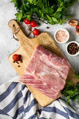 Raw pork carbonade on a wooden plate on the light gray kitchen table. Raw pork meat, tenderloin