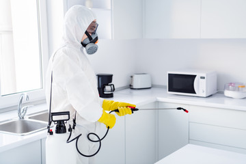 Profile side photo of focused worker cleaner in coverall guy spray sprayer kitchen stop spread ncov contamination epidemic in kitchen house indoors