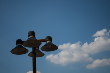 black lamp post against blue cloudy sky