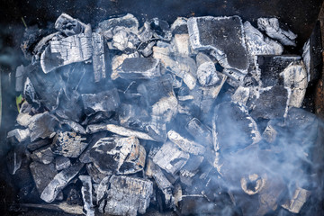 coals smolder in a barbecue with smoke