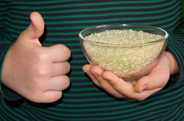 The child holds a glass plate with rice in his left hand, and shows Like with his right hand.