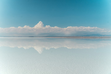 Obraz premium Blue Sky Clouds Mirror Reflection. Cloud Sky reflect on water surface of Bolivia's Salt Flats. Empty space in landscape. Holiday, vacation, freedom scene with horizon. Salar de Uyuni salt flat