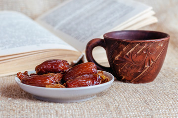 A plate of dates and raisins near a cup of coffee and an open book