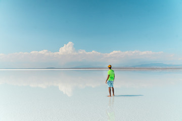Naklejka premium Travel. Man. Salt Flats Uyuni Bolivia. Tourist on beautiful mirror reflection on blue sky and cloud. DRONE Shot in Salar de Uyuni salt flat. Holiday, love, adventure vacation honeymoon travel
