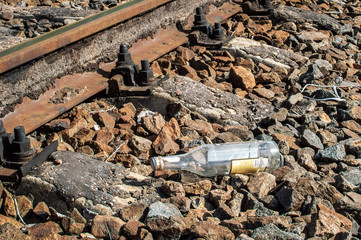 An empty glass alcohol bottle is lying near the railway. Garbage on the railway. Drunkenness among railway workers.