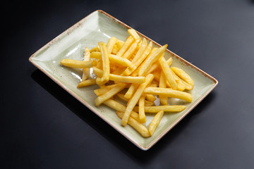 french fries in a plate on a dark background