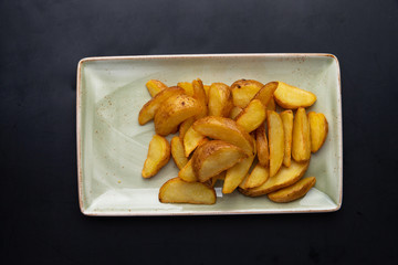 fried potato wedges in a plate on a dark background
