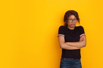 Offended as a child. African-american young woman's portrait isolated on yellow studio background. Beautiful female curly model. Concept of human emotions, facial expression, sales, ad, youth.
