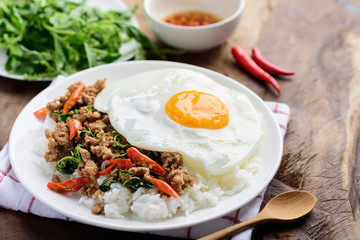 Thai food, stir-fried holy basil with minced pork and fried egg  (Pad Kaprao Moo Kai Dao) on wooden background