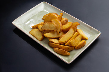 fried potato wedges in a plate on a dark background