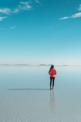 Travel. Woman. Salt Flats Uyuni Bolivia. Tourist girl on beautiful mirror reflection on blue sky and cloud. DRONE Shot in Salar de Uyuni salt flat. Holiday, love, adventure vacation honeymoon travel