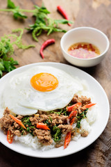 Thai food, stir-fried holy basil with minced pork and fried egg  (Pad Kaprao Moo Kai Dao) on wooden background