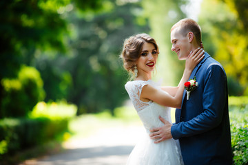 Bride and groom on their wedding day, walking outdoors in nature.