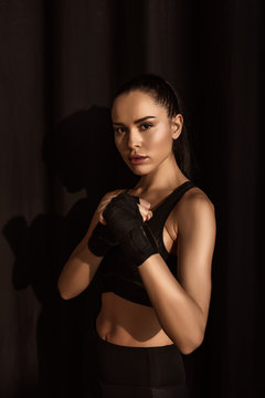 Sportswoman in fighting position looking at camera on black