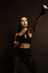 Fototapeta na wymiar Beautiful sportswoman in sports gloves with outstretched hand isolated on black