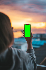 Fototapeta premium Woman holding a smartphone on a green screen
