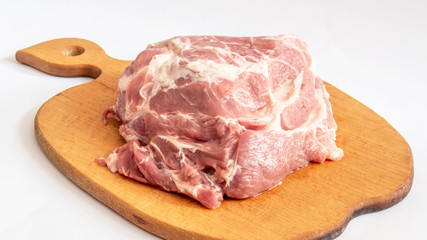 a large piece of raw pork on a wooden Board on an isolate