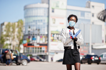 Fototapeta premium African woman wearing disposable medical mask and gloves walking outdoor during epidemic time.