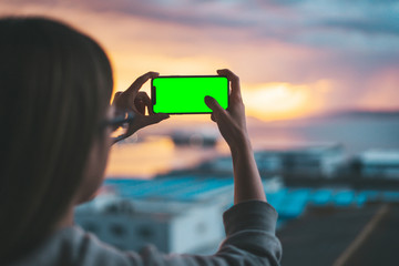 Pair of hands holding a smartphone on a green screen