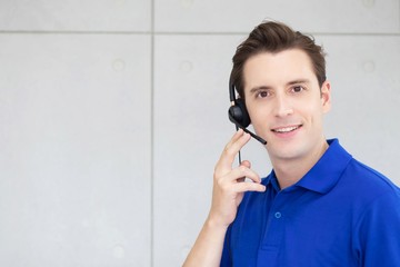 call centre. close up portrait smiling friendly handsome face man blue shirt operator working with...