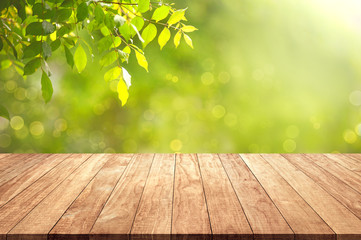Wooden table top with greenery of fresh branch of green leves after raining background