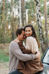 Naklejka premium beautiful young couple in love kisses and hugs sitting on a car
