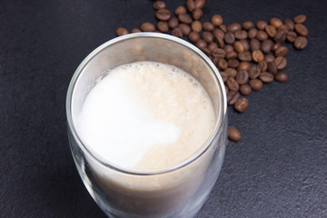 cup of latte cofee and coffee seeds on black background