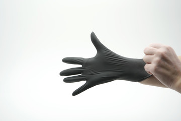 Close-up of a hand that is wearing a medical, latex, nitrile, black glove on a white background.